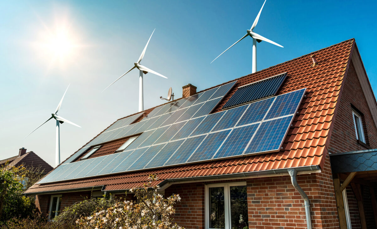 Solar panel on a roof of a house and wind turbins arround - concept of sustainable resources